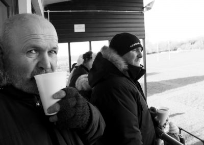 Two dads watch their boys play rugby